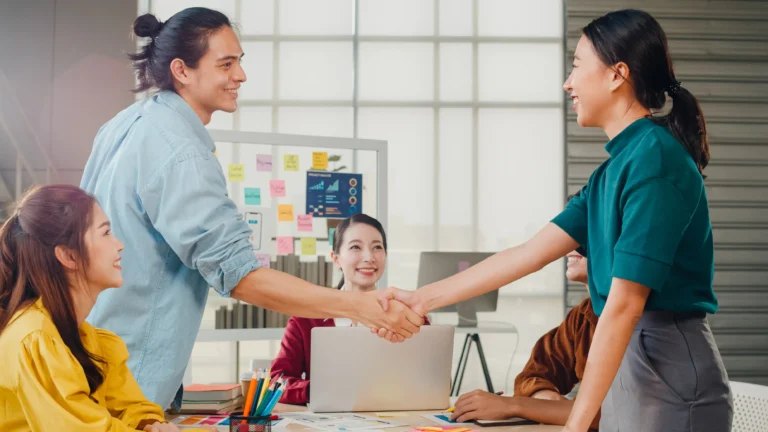 multiracial-group-young-creative-people-smart-casual-wear-discussing-business-shaking-hands-together-smiling-while-standing-modern-office-partner-cooperation-coworker-teamwork-concept